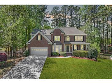 Charming two-story brick home with a well-manicured lawn, attached garage, and inviting front porch at 3918 Windgrove Xing, Suwanee, GA 30024
