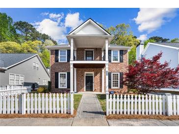 Charming two-story brick home featuring a cozy front porch, black shutters, and a picket fence at 4606 Liberty Square Dr, Acworth, GA 30101