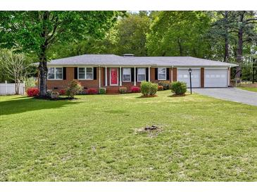 Charming brick home featuring a well-manicured lawn, colorful flowers, and a two-car garage at 241 Burke Cir, Mcdonough, GA 30253