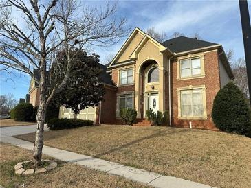 Traditional two-story brick home featuring a manicured lawn and a welcoming arched entryway at 3270 Moon Beam Ct, Snellville, GA 30039