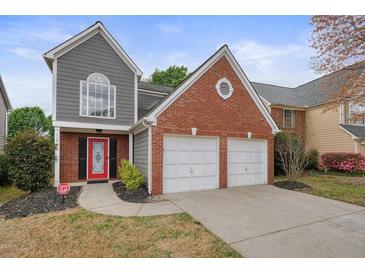 Two-story home showcasing a red brick and gray siding, two-car garage, and landscaped front yard at 1265 Birchwood Ln, Roswell, GA 30076