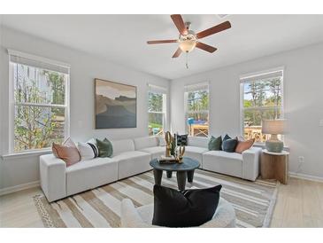 Bright living room with modern decor, large windows, and a ceiling fan for a comfortable living space at 148 Werner Brook Sw Way, Atlanta, GA 30354