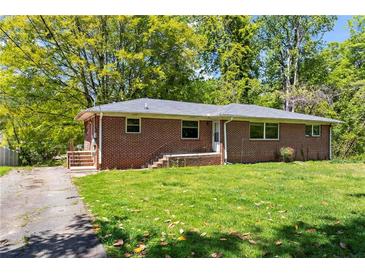Charming single-story brick home with mature trees and a well-maintained lawn at 2307 Woodridge Dr, Marietta, GA 30066