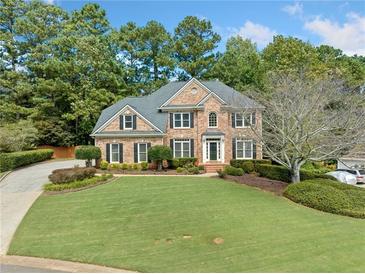 Brick two-story home with manicured lawn, mature trees, and a long driveway in a desirable neighborhood at 374 Meadowmeade Cv, Lawrenceville, GA 30043