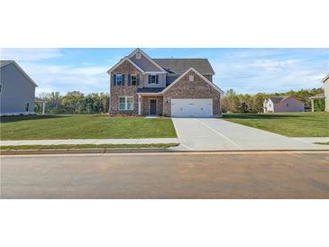 New two story brick home featuring a two car garage, well manicured lawn, and classic architectural design at 115 Felicity Pike, Locust Grove, GA 30248