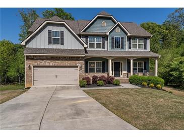 Charming two-story home with a brick-accented garage, inviting front porch, and meticulously manicured landscaping at 19 Four Feathers Ne Ln, Rydal, GA 30171