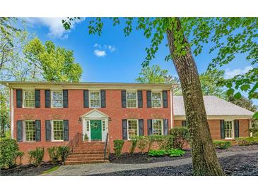 Classic brick home featuring black shutters and a vibrant green front door, set against a blue sky at 5251 Amberbrook Ct, Marietta, GA 30068