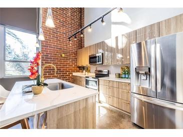 Modern kitchen with stainless steel appliances, a large island and exposed brick accent wall at 195 Arizona Ne Ave # 203, Atlanta, GA 30307