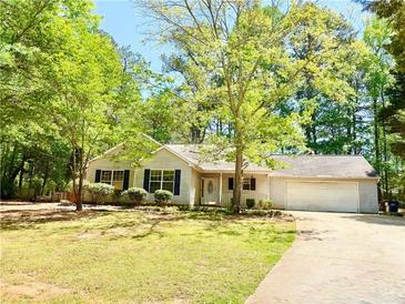 Inviting single-story home with a well-manicured lawn, lush trees, and a charming front porch at 35 Belmont Way, Covington, GA 30016