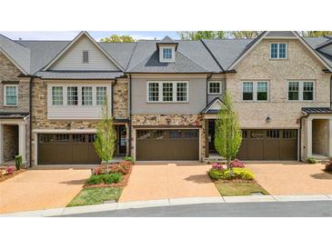 Charming townhome showcasing a two-car garage, beautiful landscaping, and stone accents at 126 Abbington River Ln, Atlanta, GA 30339