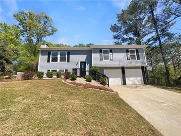 Charming two-story home featuring a well-maintained lawn and two-car garage, under a clear blue sky at 5790 Ivywood Dr, Lithonia, GA 30038