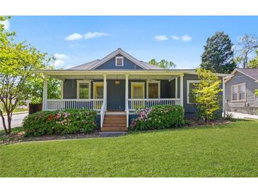 Charming home featuring a covered front porch with flowering bushes, a well-manicured lawn, and cheerful curb appeal at 873 United Se Ave, Atlanta, GA 30312