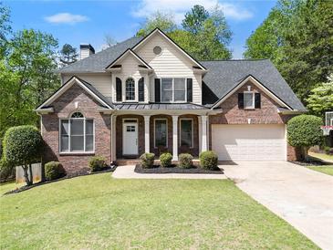 Charming two-story home featuring brick accents, a manicured lawn, and an attached two-car garage at 7665 Golden Sands Dr, Cumming, GA 30041