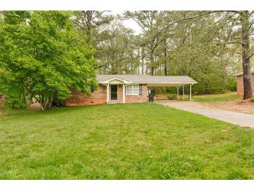 Charming brick home with a well-maintained lawn and covered carport, surrounded by mature trees at 5032 Central Church Rd, Douglasville, GA 30135