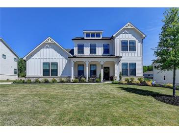 Inviting two-story home featuring a white board and batten exterior, lush lawn and covered porch at 105 Aspen Hall Dr, Canton, GA 30115