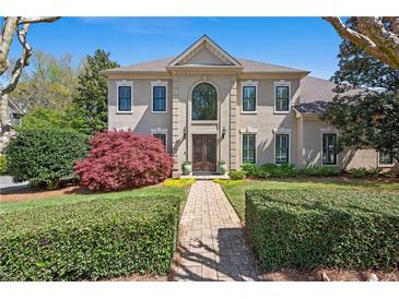 Stately home featuring manicured landscaping, a brick pathway, and a symmetrical facade with large arched window at 18 Rose Gate Ne Dr, Atlanta, GA 30342