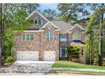 Two-story brick home featuring a two-car garage, well-manicured lawn, and mature trees in a suburban setting at 360 Beracah Sw Trl, Atlanta, GA 30331