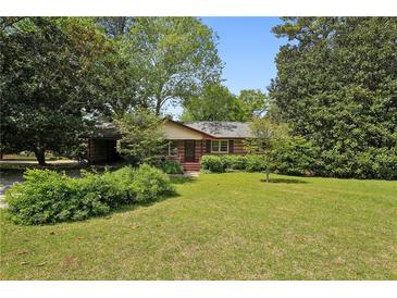 Charming one-story home featuring a lush front lawn and mature trees on a sunny day at 1911 Lavista Ne Rd, Atlanta, GA 30329