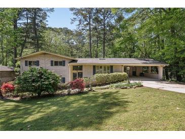 Charming brick home with a well-manicured lawn, mature trees, and a convenient attached carport at 1496 Country Squire Dr, Decatur, GA 30033