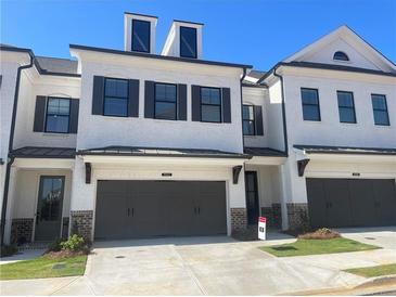 Charming townhome featuring a brick and white exterior with a two-car garage and inviting front entrance at 5022 Buice Crest Court, Buford, GA 30518