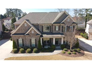 Beautiful two-story brick home featuring a well-manicured lawn and inviting front porch area at 4881 Belle Estates Rd, Suwanee, GA 30024