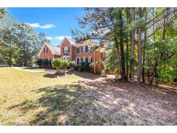 Charming two-story brick home with mature trees in a lush green lawn at 1085 Crown River Pkwy, Mcdonough, GA 30252