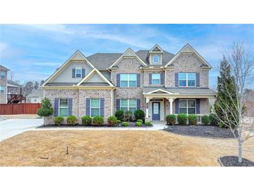 Beautiful two story brick home with well manicured lawn and blue shutters set under a beautiful blue sky at 5525 Nesmith Ct, Cumming, GA 30040