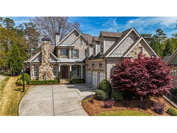 Stunning two-story home featuring a stone chimney, three-car garage, and beautifully landscaped front yard at 3318 Monceau Way, Roswell, GA 30075