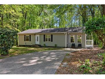 Charming single-story home featuring a well-maintained lawn and a cozy front porch nestled in a lush, wooded setting at 3690 Asbury Sw Ln, Atlanta, GA 30331