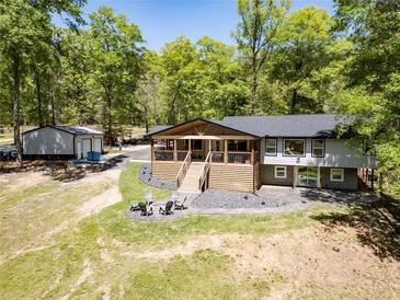 Beautiful home exterior featuring a covered porch, wood accents, stone landscaping, and large mature trees at 125 Mayo Rd, Covington, GA 30014