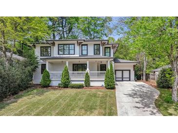 Charming two-story home featuring a manicured front lawn, classic white columns, and dark framed windows at 1282 Fairhill Ne Ln, Atlanta, GA 30319