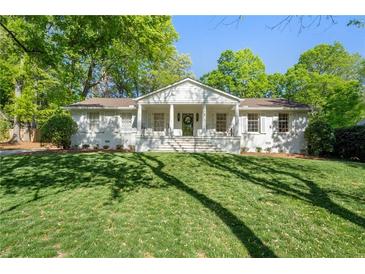 Charming one-story white home with a landscaped yard and beautiful lawn at 1305 Old Woodbine Rd, Atlanta, GA 30319