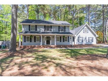 Charming two-story home features a large, covered front porch, and mature trees enhancing the landscape at 714 Lanford Springs Sw Dr, Lilburn, GA 30047