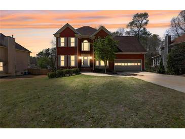 Charming brick two-story home with a well-manicured lawn and attached two car garage at sunset at 2433 Idlewood Way, Snellville, GA 30078
