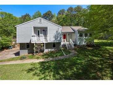 Charming two-story home featuring a covered balcony and a walkway surrounded by lush greenery at 6500 Chickasaw Dr, Douglasville, GA 30135