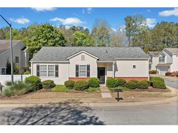 Charming single-story home featuring a well-manicured lawn and a classic design with black shutters at 1228 W Oaks Way, Woodstock, GA 30188
