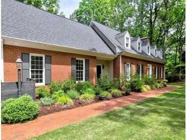 Charming brick home featuring a well-manicured lawn, beautiful landscaping and a red brick walkway at 1250 Northcliff Trce, Roswell, GA 30076