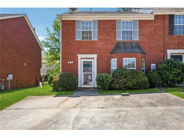 Charming brick townhome featuring a neatly landscaped front yard and private parking at 5679 Windfall Ln, Lithonia, GA 30058