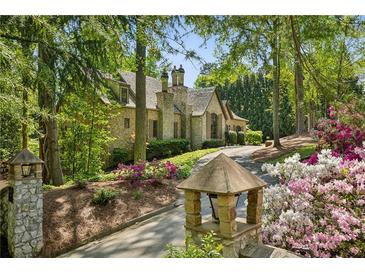 Charming stone home with lush landscaping and a private driveway nestled among mature trees at 105 Kingston Mnr, Atlanta, GA 30342