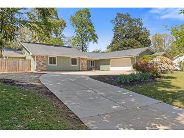 Charming single-story home with a stone facade, light-green wood siding, and a spacious concrete driveway at 350 Somerset Se Ln, Marietta, GA 30067