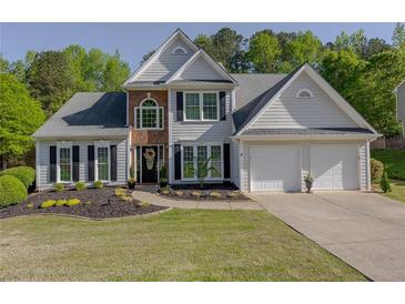 Charming two-story home features a well-manicured lawn, two-car garage, and inviting front entrance at 513 Huntgate Rd, Woodstock, GA 30189
