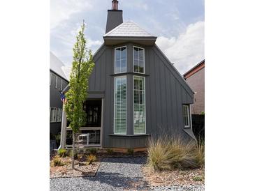 Charming gray home with tall windows and gravel pathway, surrounded by lush landscaping and a unique roofline at 135 Channing Ln, Fayetteville, GA 30214