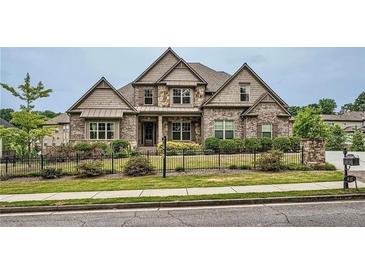 Beautiful two-story home with stone and siding, complimented by a meticulously maintained lawn and wrought iron fence at 631 Mabry Rd, Sandy Springs, GA 30328