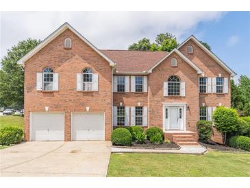 Elegant brick home featuring a two-car garage, manicured lawn, and symmetrical window shutters at 1241 Hogan Ridge Ct, Grayson, GA 30017