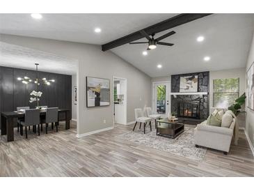 Open-concept living room features a black stone fireplace, beamed ceilings, and wood-look floors at 4983 Needle Knob Ct, Lithonia, GA 30038