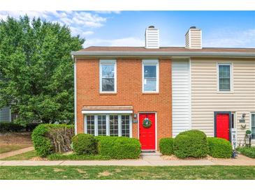 Charming brick townhome featuring a bright red front door and meticulously maintained landscaping at 197 Holcomb Ferry Rd, Roswell, GA 30076
