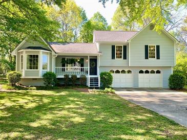 Charming home featuring a well-manicured lawn, inviting front porch, and attached two-car garage at 1835 Penrose Ct, Powder Springs, GA 30127