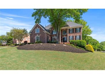 Stately brick home boasts a lush landscaped front yard and classic architectural details at 605 Tatum Ct, Alpharetta, GA 30022