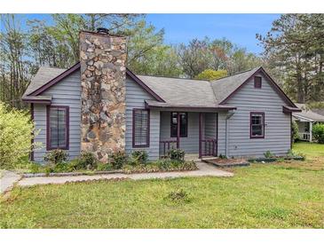 Charming gray home featuring a stone chimney, inviting front porch, and well-maintained landscaping at 285 Independence Dr, Jonesboro, GA 30238