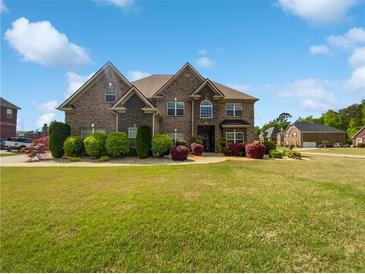 Beautiful two-story brick home with a lush green lawn and manicured landscaping at 400 Icicle Ct, Hampton, GA 30228
